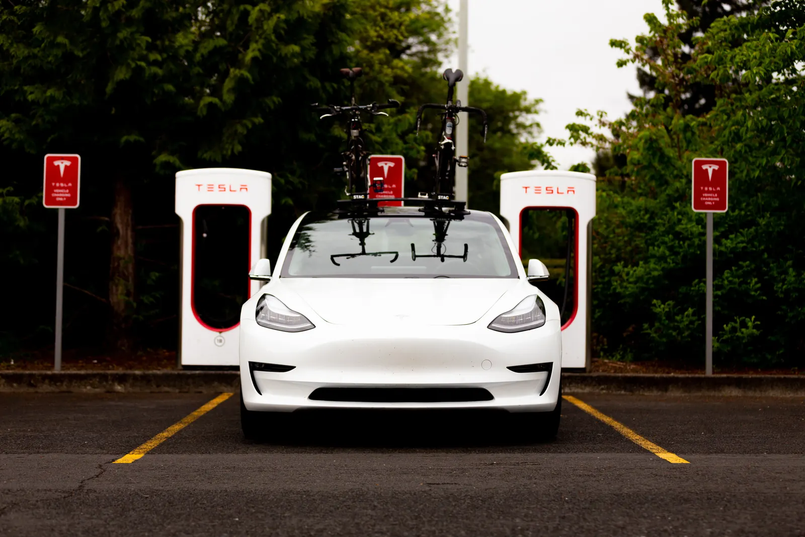 Two bikes on a STAG Rack on a white Tesla at a Supercharger
